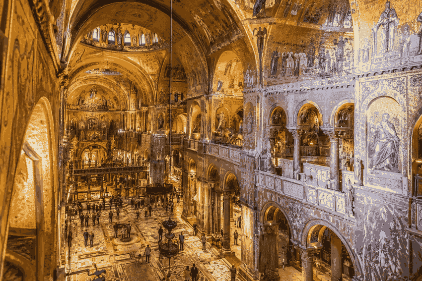 Interior of St. Mark’s Basilica in Venice showing its golden mosaics, ornate arches and marble floors.